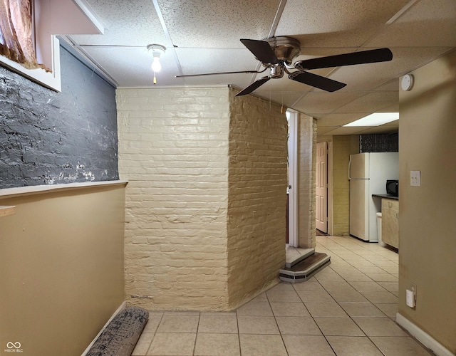 hall featuring a drop ceiling and light tile patterned flooring