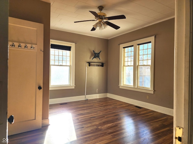 spare room featuring a healthy amount of sunlight, dark hardwood / wood-style floors, and crown molding