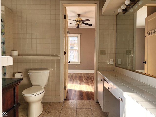 bathroom featuring tile patterned floors, vanity, ceiling fan, tile walls, and toilet