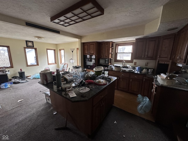 kitchen featuring dark brown cabinetry, a center island, dark carpet, and a textured ceiling