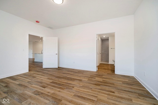 unfurnished bedroom featuring wood-type flooring and ensuite bath