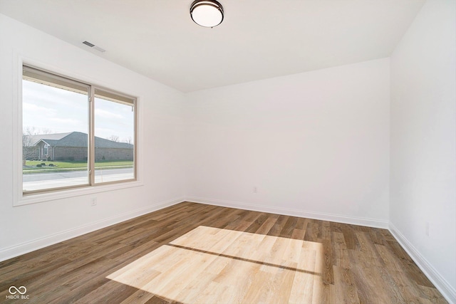 empty room with visible vents, baseboards, and wood finished floors