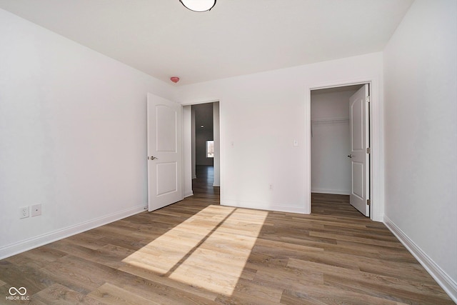 unfurnished bedroom with hardwood / wood-style flooring, a walk in closet, and a closet