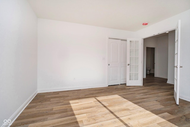 unfurnished bedroom with wood-type flooring, french doors, and a closet