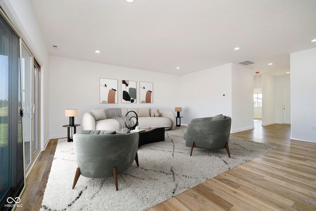 living area featuring baseboards, light wood-style flooring, visible vents, and recessed lighting