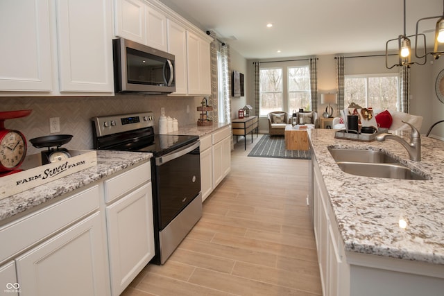 kitchen featuring decorative backsplash, appliances with stainless steel finishes, light stone counters, sink, and white cabinets