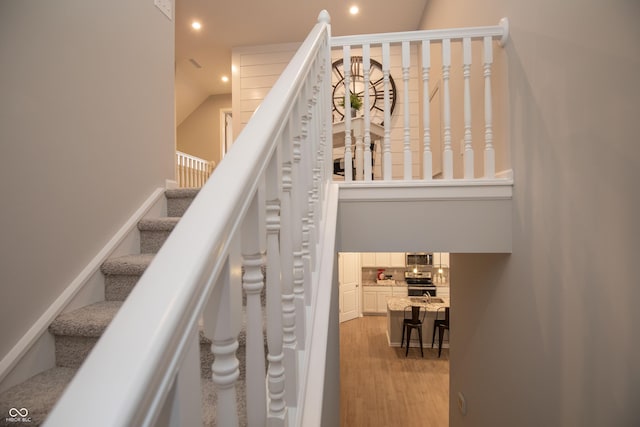 stairs with hardwood / wood-style flooring and vaulted ceiling