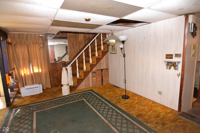 basement with a paneled ceiling and wooden walls