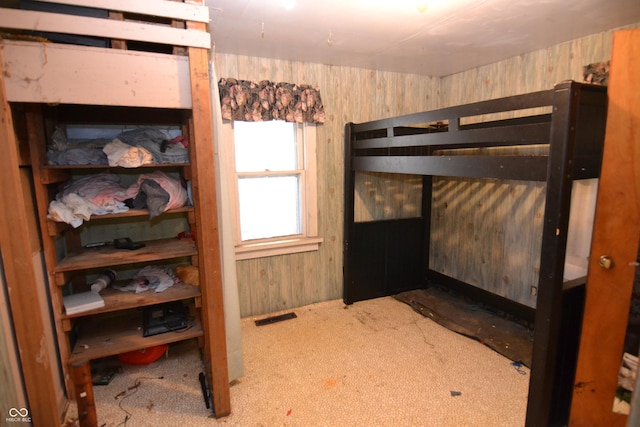 bedroom featuring wood walls and light carpet