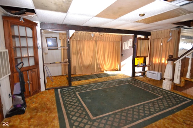 interior space featuring a paneled ceiling and wood walls