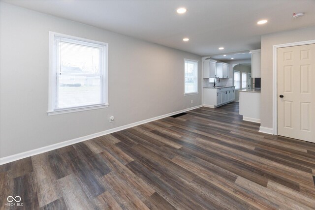 unfurnished living room with dark hardwood / wood-style flooring and sink