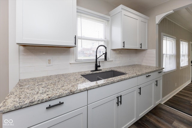 kitchen with light stone countertops, sink, dark wood-type flooring, tasteful backsplash, and white cabinets