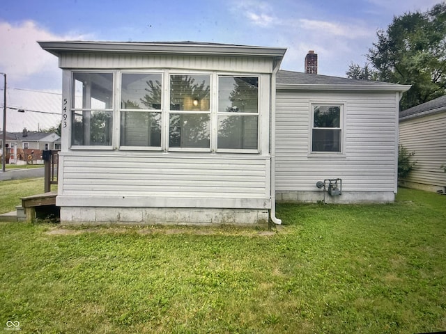 property exterior at dusk featuring a sunroom and a yard