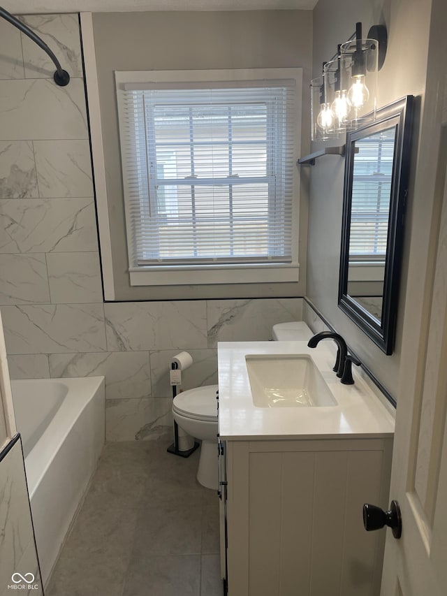 full bathroom with tile patterned floors, tile walls, toilet, vanity, and shower / bathtub combination