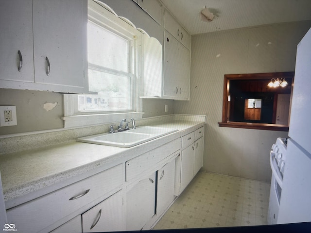 kitchen featuring white range with electric stovetop, sink, and white cabinets