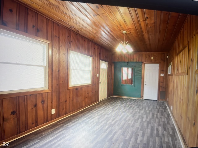 unfurnished room with dark hardwood / wood-style floors, an inviting chandelier, a healthy amount of sunlight, and wood walls