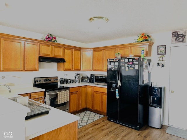 kitchen featuring light hardwood / wood-style floors, kitchen peninsula, sink, and appliances with stainless steel finishes