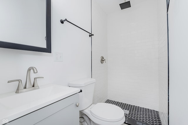 bathroom with vanity, toilet, and tiled shower