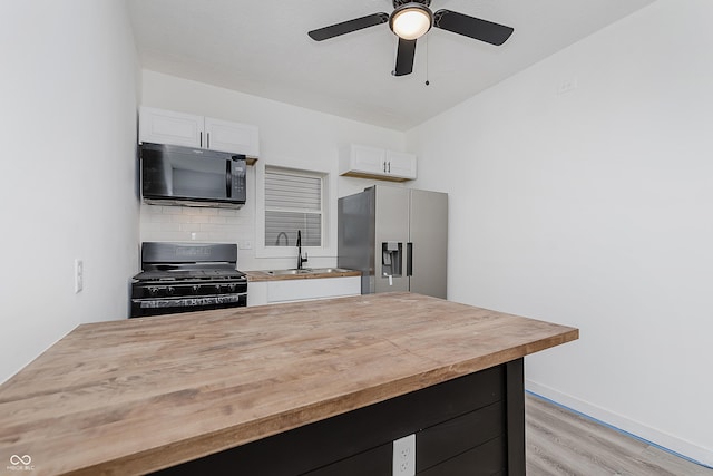 kitchen with sink, tasteful backsplash, light hardwood / wood-style flooring, white cabinets, and black appliances