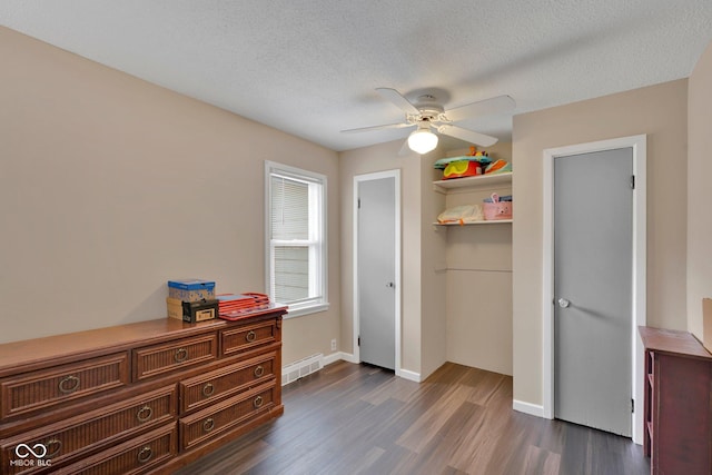 bedroom with a textured ceiling, ceiling fan, and dark wood-type flooring