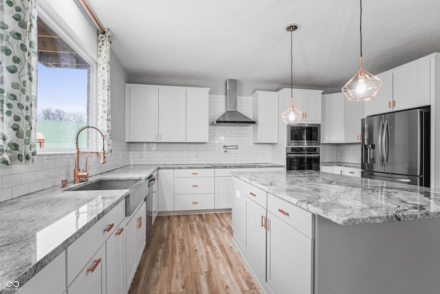 kitchen with backsplash, white cabinets, light stone countertops, wall chimney range hood, and stainless steel appliances