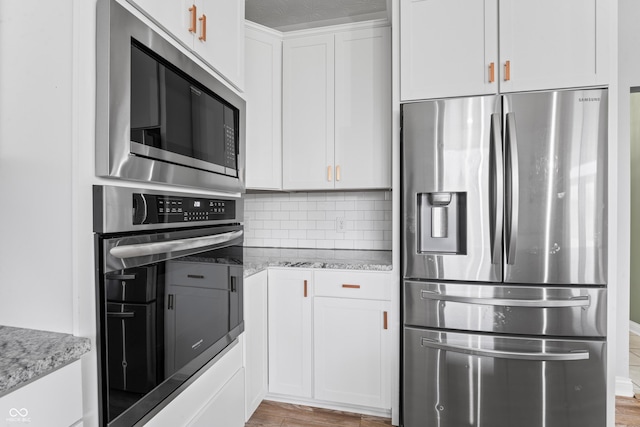 kitchen featuring light hardwood / wood-style floors, stainless steel appliances, white cabinetry, and light stone countertops