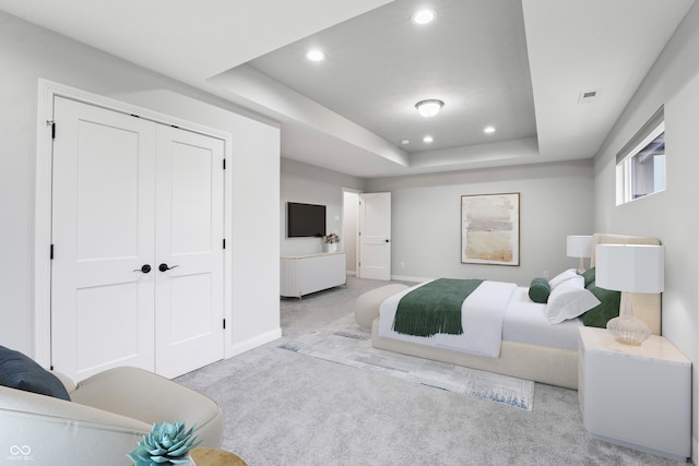 carpeted bedroom featuring a closet and a raised ceiling