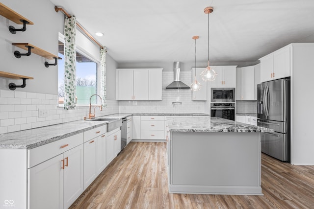 kitchen featuring white cabinetry, wall chimney range hood, appliances with stainless steel finishes, and a kitchen island