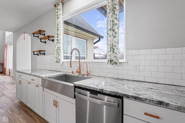 kitchen with light hardwood / wood-style floors, light stone countertops, dishwasher, white cabinets, and sink