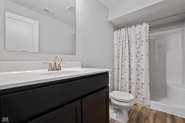 bathroom with wood-type flooring, toilet, walk in shower, and vanity