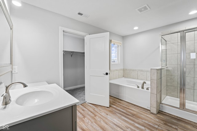 bathroom with hardwood / wood-style flooring, vanity, and shower with separate bathtub