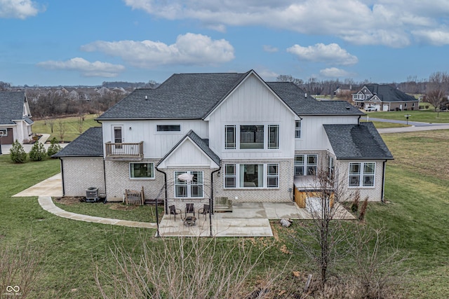 rear view of property featuring a patio, a balcony, central AC unit, and a lawn