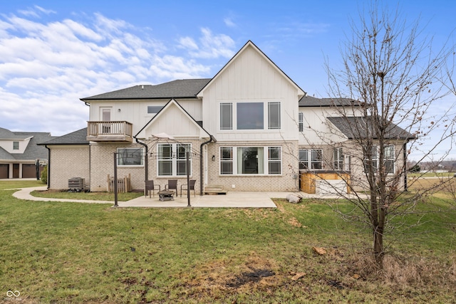 rear view of property with a balcony, a yard, central AC unit, and a patio