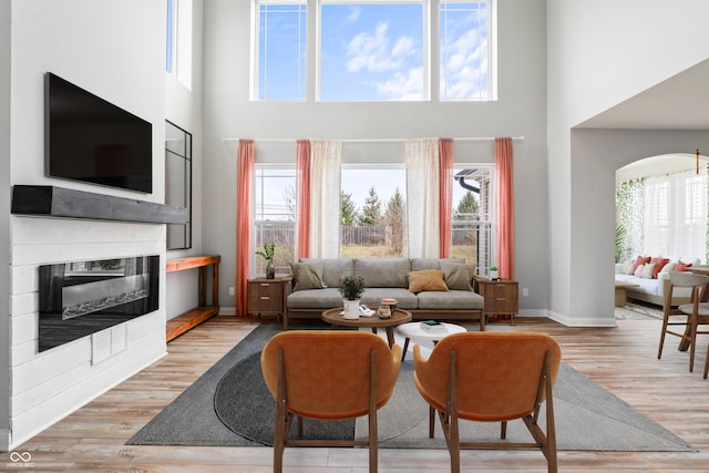 living room with light hardwood / wood-style flooring and a towering ceiling