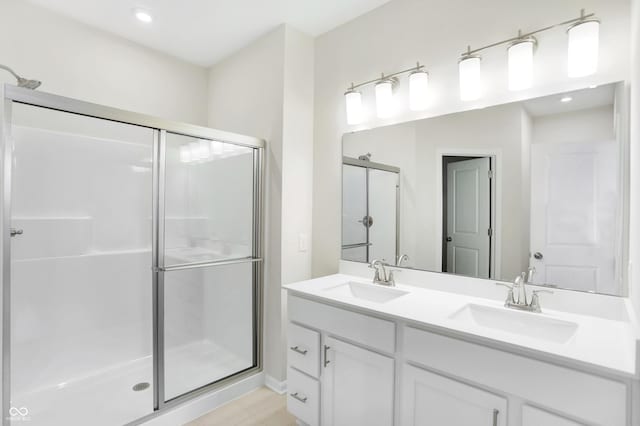 bathroom with hardwood / wood-style floors, vanity, and an enclosed shower