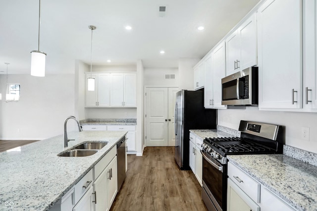 kitchen featuring white cabinets, appliances with stainless steel finishes, pendant lighting, and sink