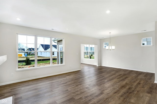 unfurnished living room featuring dark hardwood / wood-style floors and an inviting chandelier