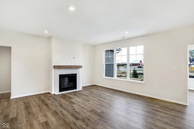 unfurnished living room featuring a tile fireplace and dark hardwood / wood-style flooring