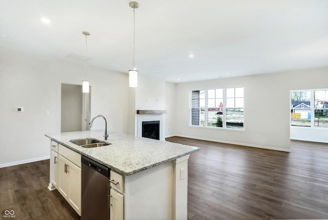 kitchen with white cabinetry, sink, hanging light fixtures, light stone counters, and stainless steel dishwasher