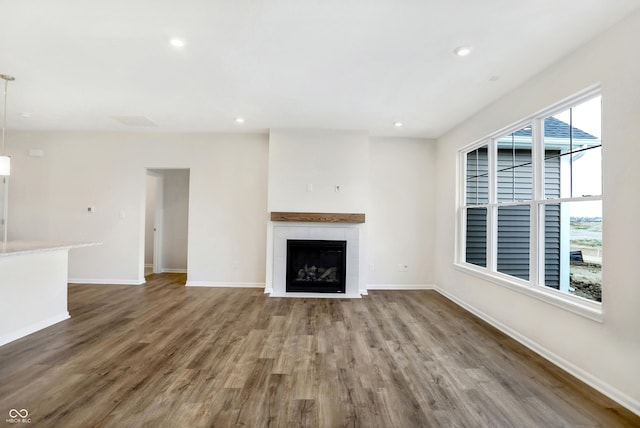 unfurnished living room with hardwood / wood-style flooring and a tiled fireplace