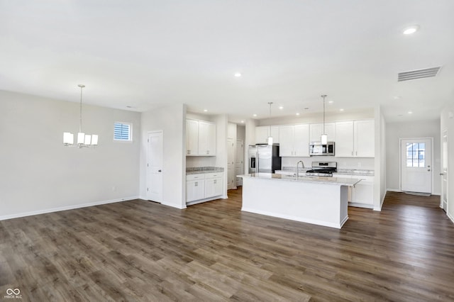 kitchen featuring decorative light fixtures, white cabinetry, stainless steel appliances, and an island with sink