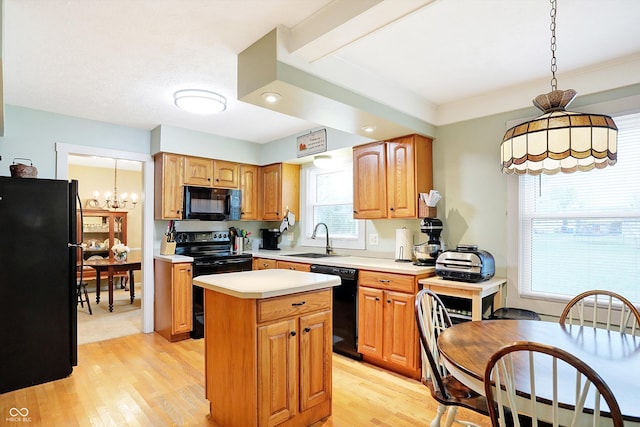 kitchen with a center island, black appliances, sink, hanging light fixtures, and light hardwood / wood-style flooring