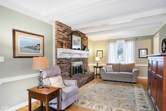 living room with beam ceiling, light hardwood / wood-style flooring, and a brick fireplace