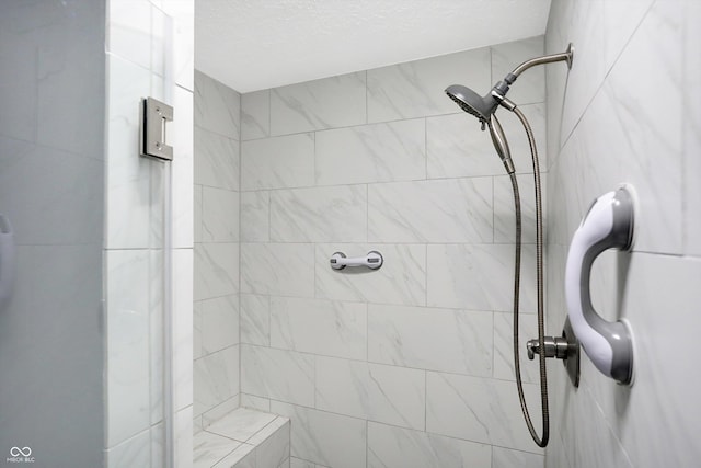 bathroom featuring a tile shower and a textured ceiling