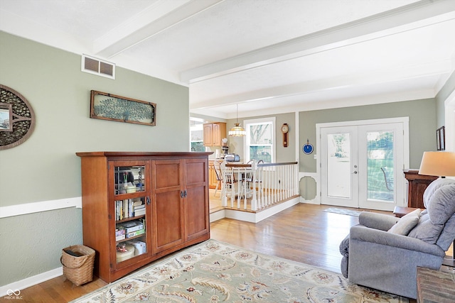 interior space with beamed ceiling, french doors, light wood-type flooring, and an inviting chandelier