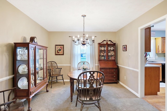 dining space with light carpet, sink, and a chandelier