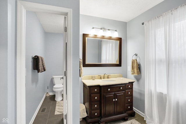 bathroom featuring tile patterned flooring, vanity, a textured ceiling, and toilet