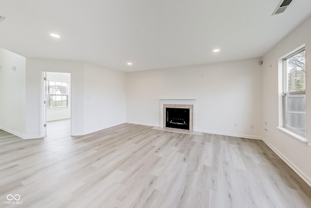 unfurnished living room featuring a fireplace, light hardwood / wood-style floors, and a healthy amount of sunlight