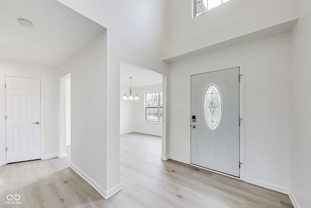 entryway with light hardwood / wood-style floors and an inviting chandelier