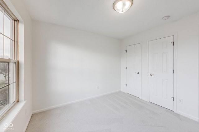 unfurnished bedroom with light carpet and multiple windows